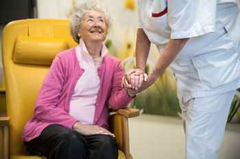 Foto van oudere vrouw in stoel met verpleegkundige