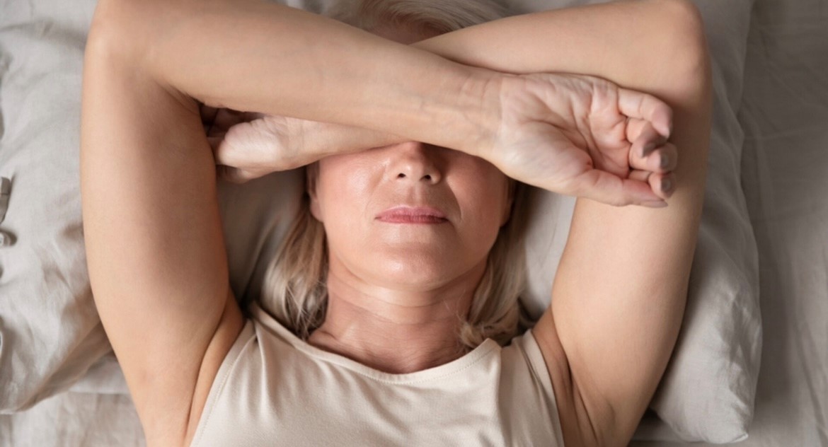 Vrouw in de overgang met armen over haar ogen