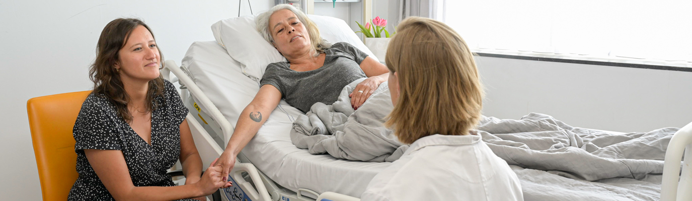 Foto van een patiënt, familielid en zorgverlener in gesprek 