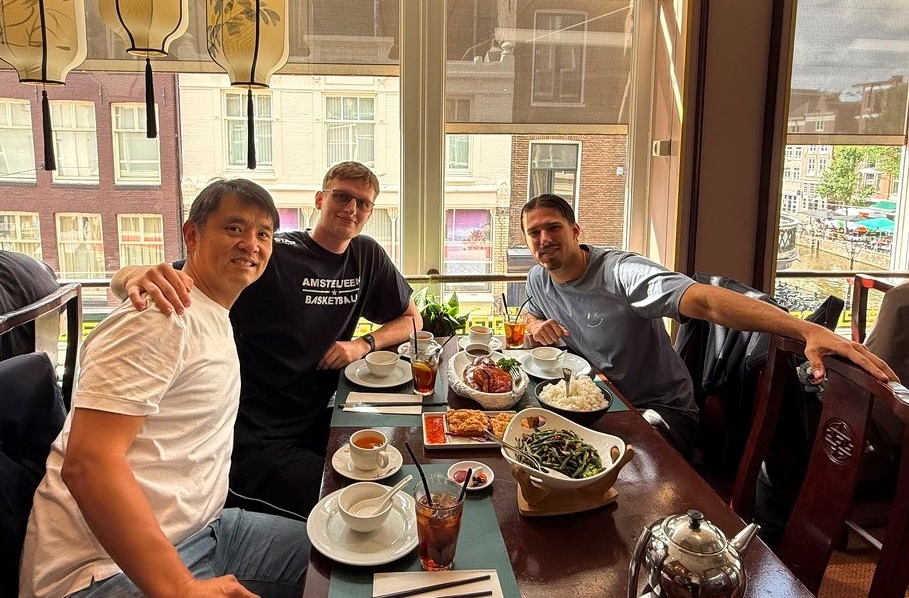 Drie mannen aan een tafel vol eten in een restaurant