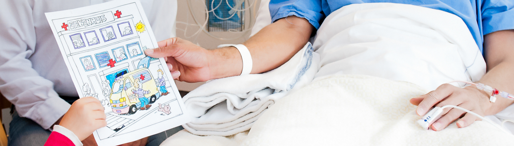 Foto van een patiënt die in bed ligt en een tekening krijgt van haar kind