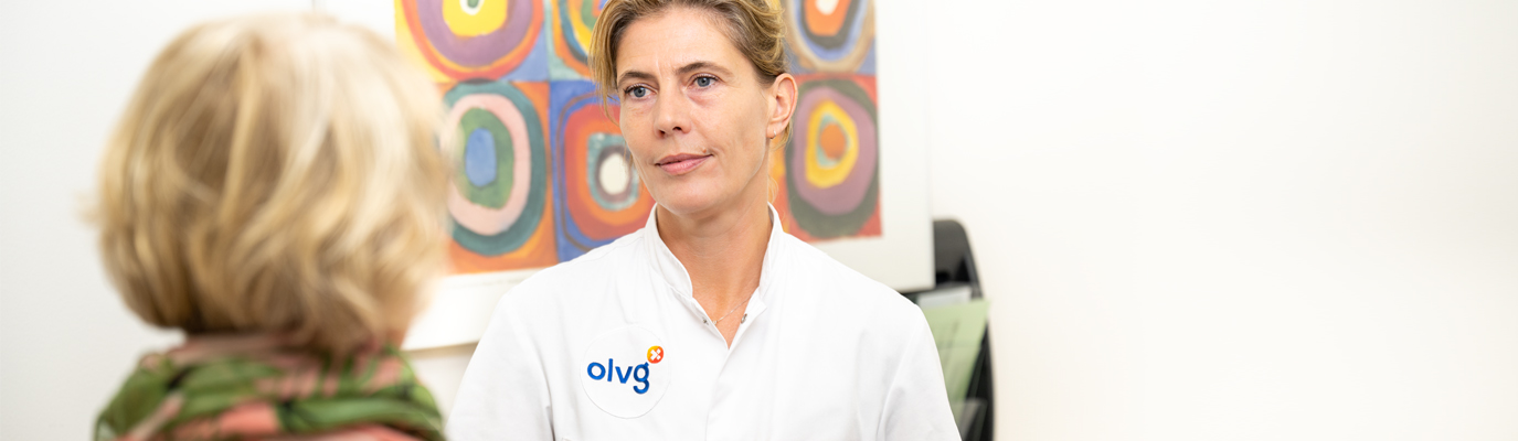 Foto van een medewerker in gesprek met een patient. 